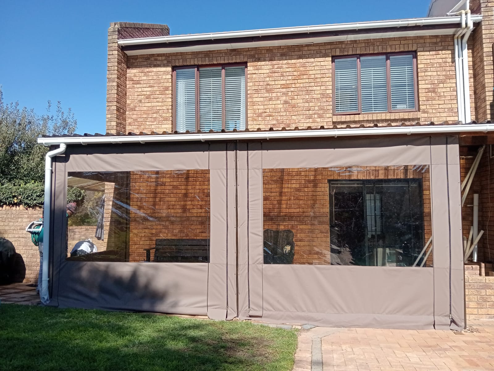 Large clear outdoor blinds enclosing a brick patio